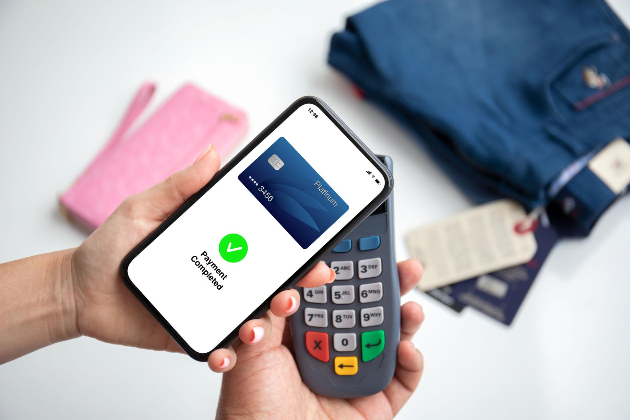 Phone showing a Payment Completed confirmation hovering over a card terminal.